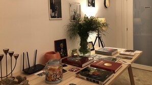 A room with a table displaying books, a vase with flowers, and framed pictures on the wall. - Ca' Lou al Teatro (Vicenza)