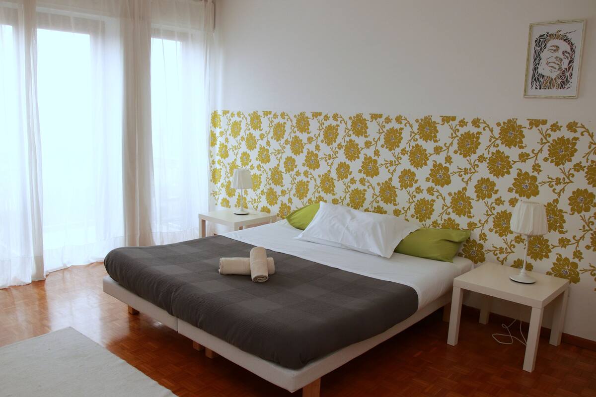 A neatly arranged bedroom with a bed, bedside tables, and a lamp.