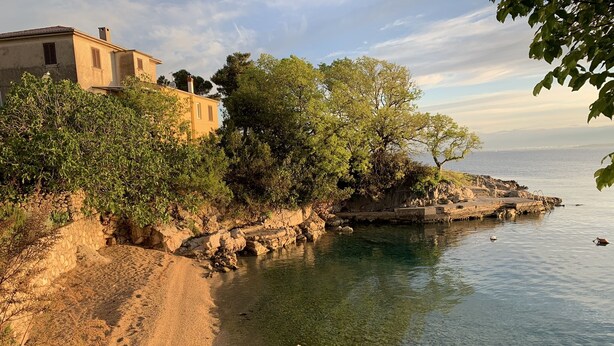 A coastal landscape with a rocky shoreline, clear water, and a building with a sloped roof. - Modern 5 * villa with pool, only 70m from the beach (Vantacici)