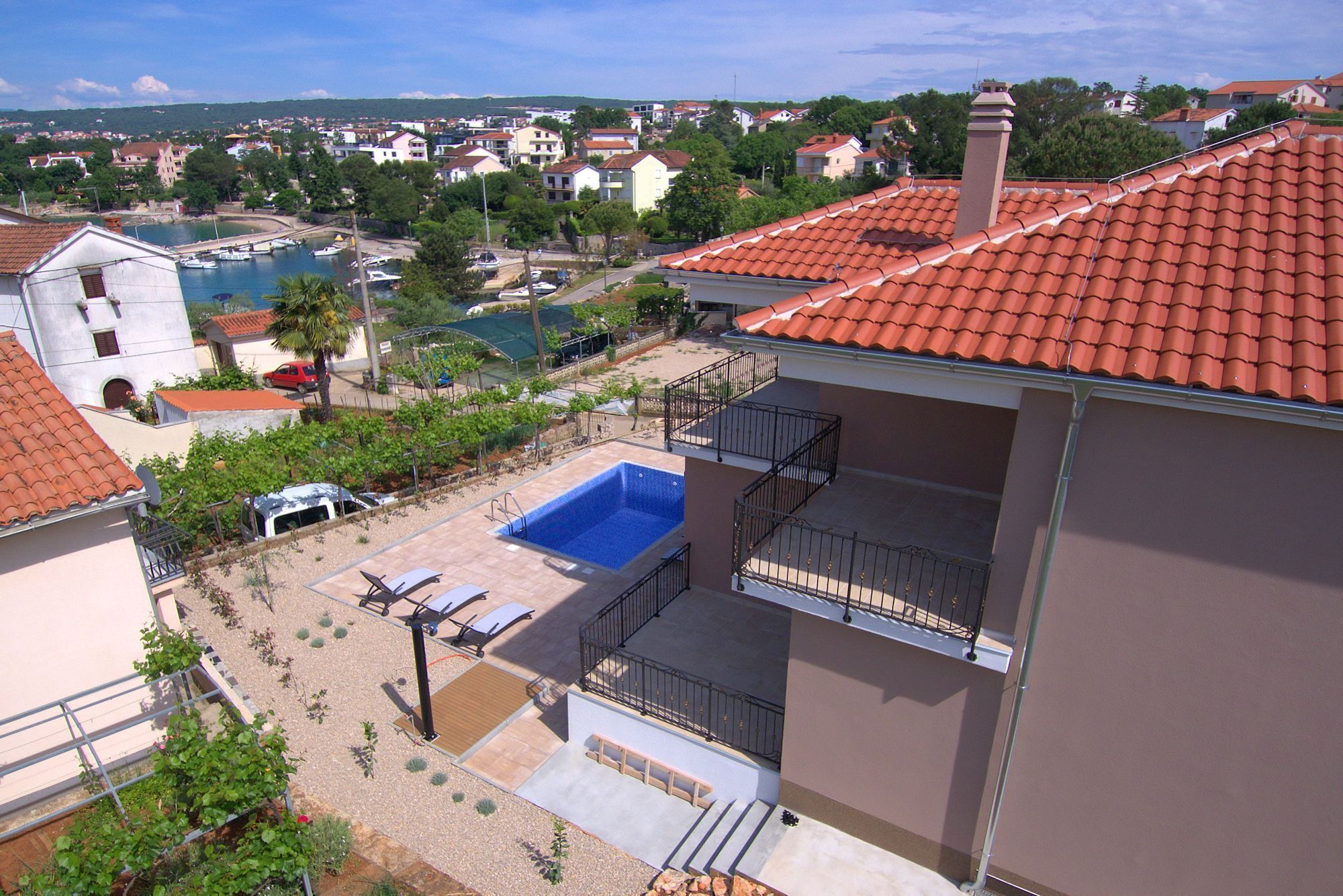 Un edificio residencial con piscina, balcón y vistas a un pueblo costero.