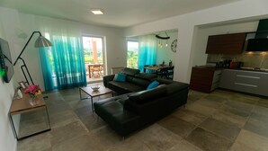 A modern living room with a black leather sofa, a wooden coffee table, and a dining area with a table and chairs. - Modern 5 * villa with pool, only 70m from the beach (Vantacici)