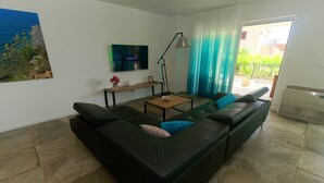 A modern living room with a black leather sofa, a coffee table, and a TV on the wall. - Modern 5 * villa with pool, only 70m from the beach (Vantacici)