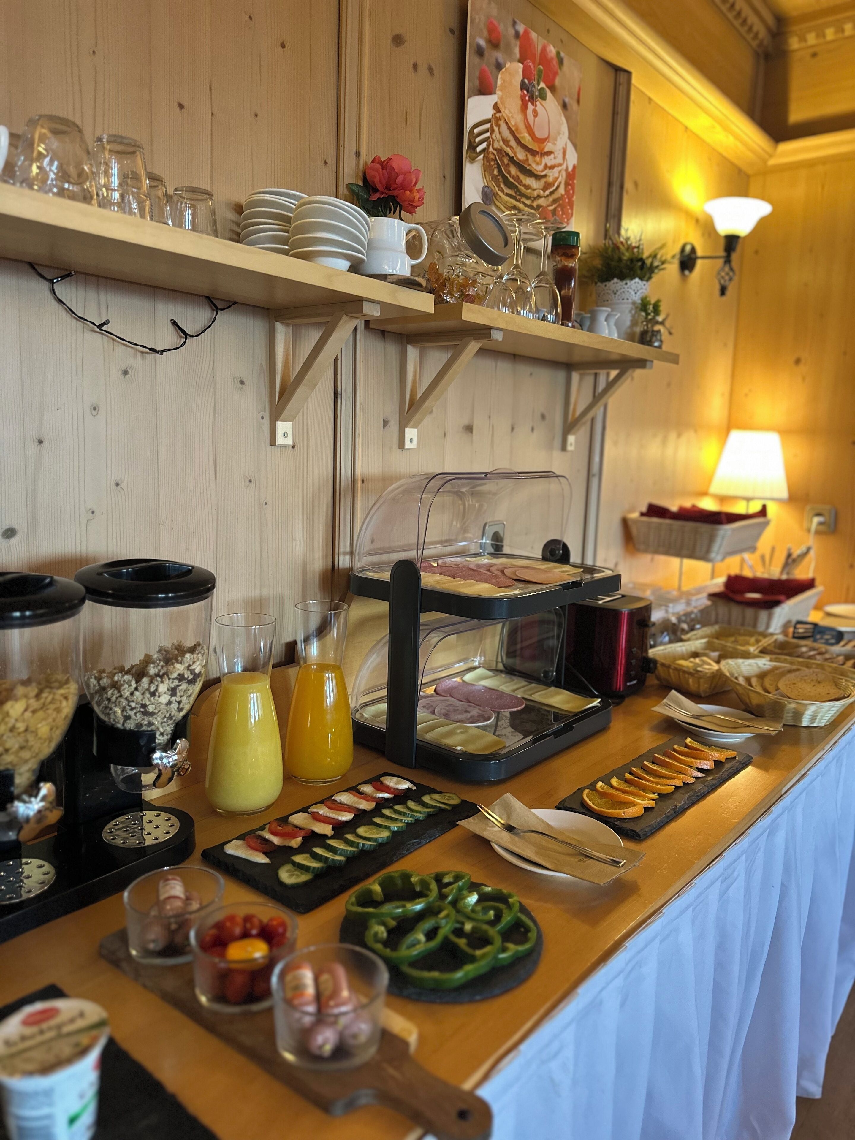 Un bufé con diversos alimentos, incluyendo frutas cortadas, verduras y una variedad de opciones para el desayuno.