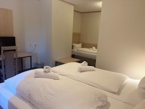 Ein Hotelzimmer mit einem Bett, zwei Handtüchern, einem Schreibtisch und einem Stuhl.