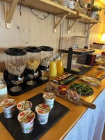 Ein Buffet mit verschiedenen Speisen, darunter Müsli, Joghurt sowie eine Auswahl an Fleisch und Gemüse.