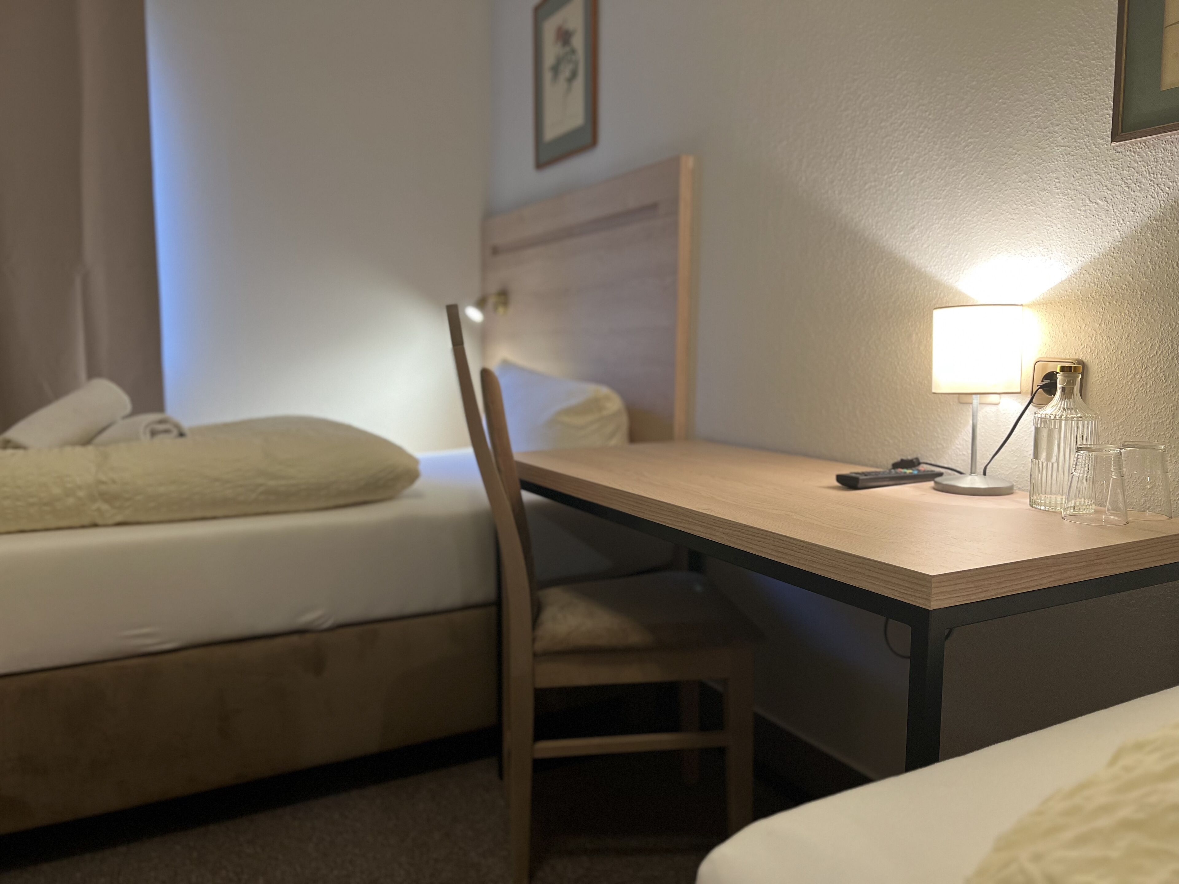 Ein Hotelzimmer mit Bett, Schreibtisch, Stuhl, Lampe und einer Flasche.
