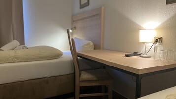 Ein Hotelzimmer mit Bett, Schreibtisch, Stuhl, Lampe und einer Flasche.