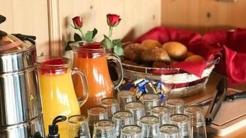 A breakfast buffet setup with a coffee maker, a pitcher of orange juice, and a bowl of fruit.