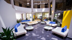 A spacious lobby with multiple seating areas, a central coffee table, and a visible restaurant named "Cheeky Monkey's." - Smartline Meridian Hotel (Sunny Beach)