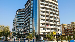 A multi-story hotel with a curved facade, balconies, and a swimming pool area with umbrellas. - Smartline Meridian Hotel (Sunny Beach)