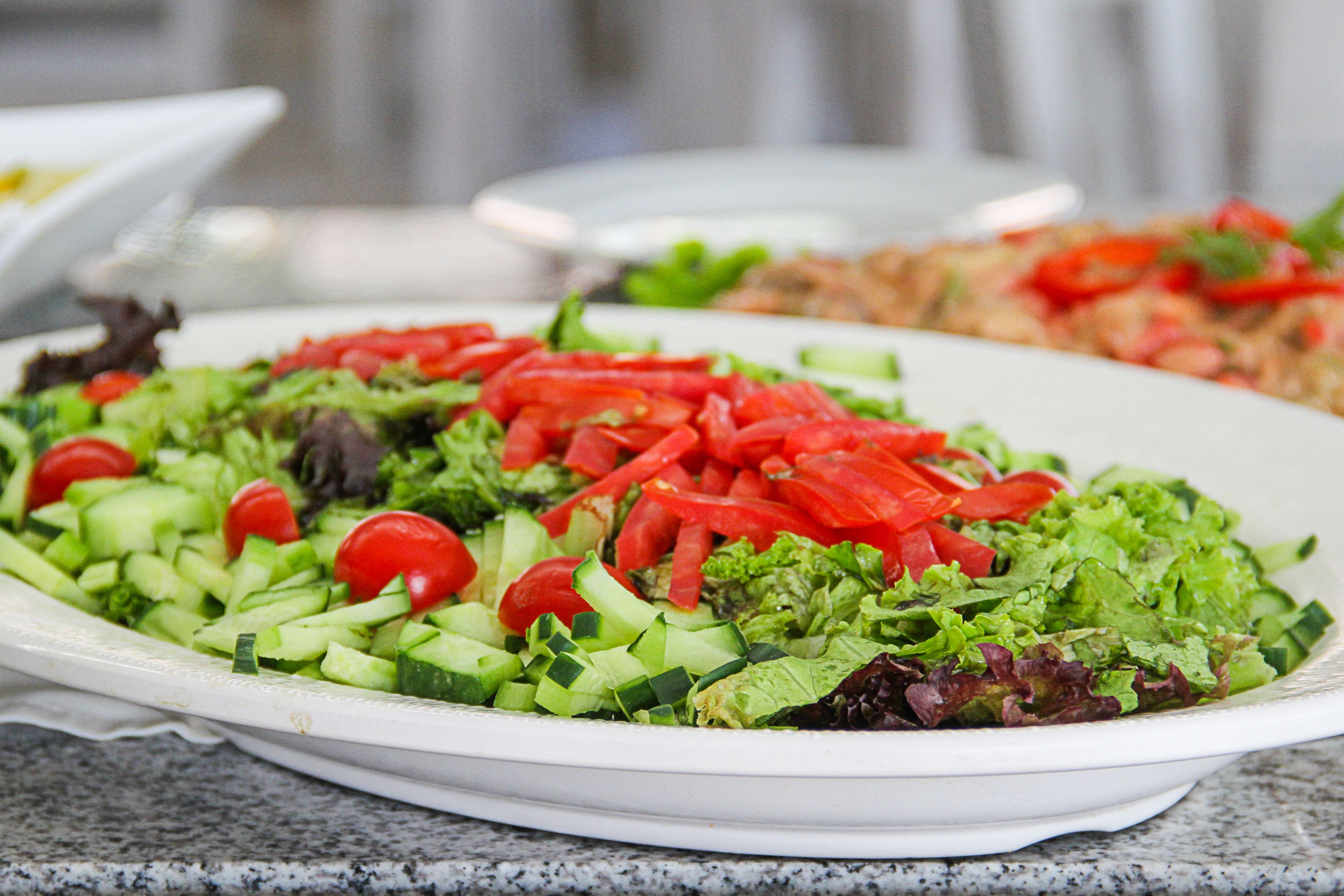 A white plate with a salad containing lettuce, tomatoes, and cucumbers.