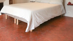A bedroom with a large bed, wooden beams on the ceiling, a fireplace, and a red object on the wall. - House Alberta Superb T2 in the city center (Aix-en-Provence)