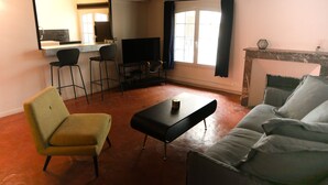 A living room with a sofa, a yellow armchair, a black coffee table, a TV, and a fireplace. - House Alberta Superb T2 in the city center (Aix-en-Provence)