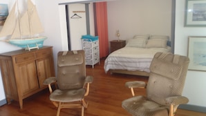 A bedroom with a bed, two wicker chairs, a wooden cabinet, and a hanging coat rack. - --- SEA AND BOATS ---- (Le Portel)