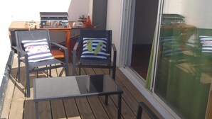 A wooden deck with two chairs and a table, a grill, and a sliding glass door. - --- SEA AND BOATS ---- (Le Portel)