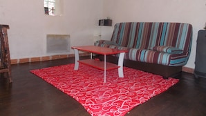 A living room with a striped sofa, a red table, and a patterned rug. - Nice little studio 20 M2 (AUPS)