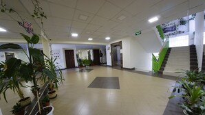 Eine geräumige Lobby mit Blumentöpfen, einer Treppe und einem Aufzug.