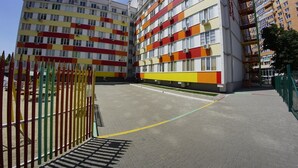 Ein mehrgeschossiges Wohnhaus mit einer farbenfrohen Fassade, einem Spielplatz und einem gepflasterten Innenhof.