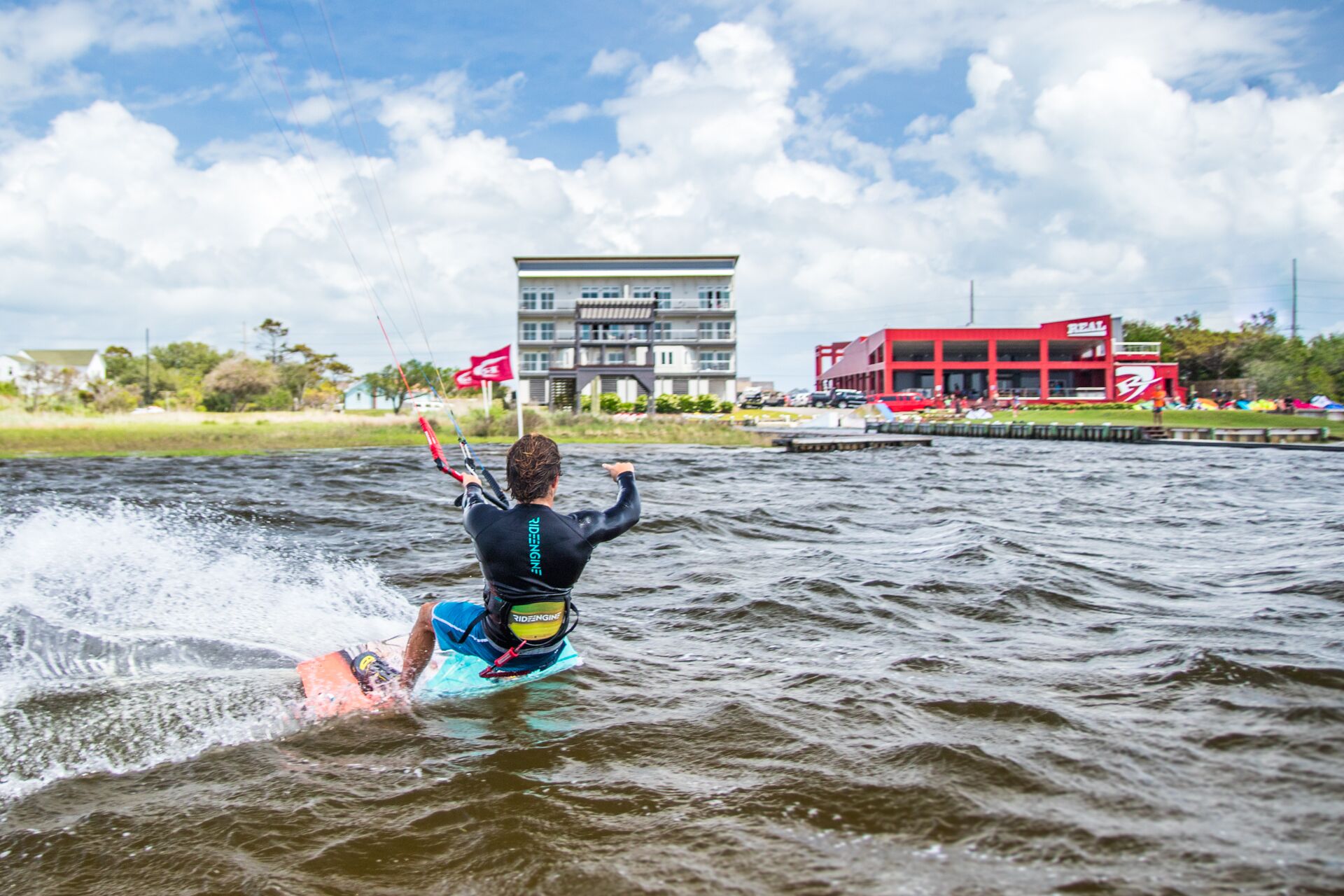 Iemand waterskiën op een wateroppervlak met gebouwen op de achtergrond.
