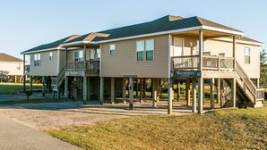 A two-story building with a covered porch and a sign that reads "Watermen's Club." - 3-bedroom, 2-bathroom apartment. Walk to beach and access to REAL Watersports (Waves)