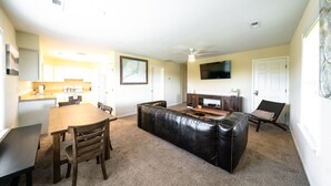 A compact living space with a dining area, a black leather couch, a TV, and a fireplace. - 3-bedroom, 2-bathroom apartment. Walk to beach and access to REAL Watersports (Waves)