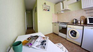 A compact kitchen with a washing machine, a stove, and a microwave. - Flatsis Apartment Otakara Yarosha 33 (Kharkiv)