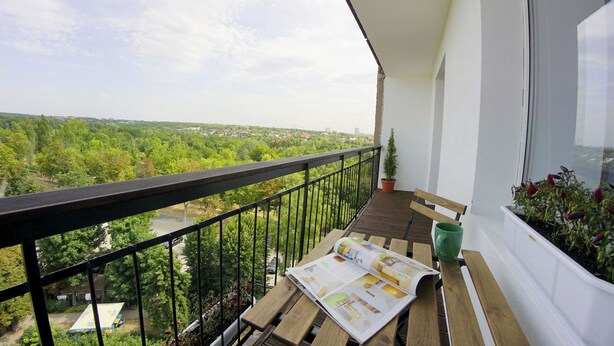 A balcony with a wooden table, a bench, and a potted plant. - Flatsis Apartment Otakara Yarosha 33 (Kharkiv)