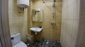 Een kleine badkamer met toilet, wastafel en douche.