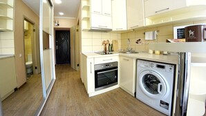 Een compacte keuken met een wasmachine, oven en een klein aanrecht.