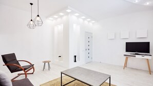 Een moderne woonkamer met een bank, een salontafel, een televisie en een fauteuil.