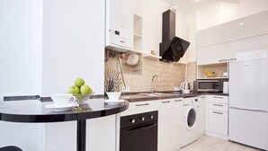 Een moderne keuken met een zwart aanrecht, witte kastjes, een ingebouwde oven, een wasmachine en een magnetron.