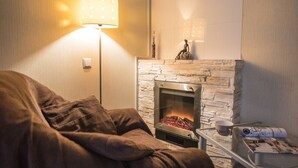 A cozy living room with a stone fireplace, a sofa, a lamp, and a small table with a magazine. - Flatsis Apartment Kuznechnaya 13 (Kharkiv)