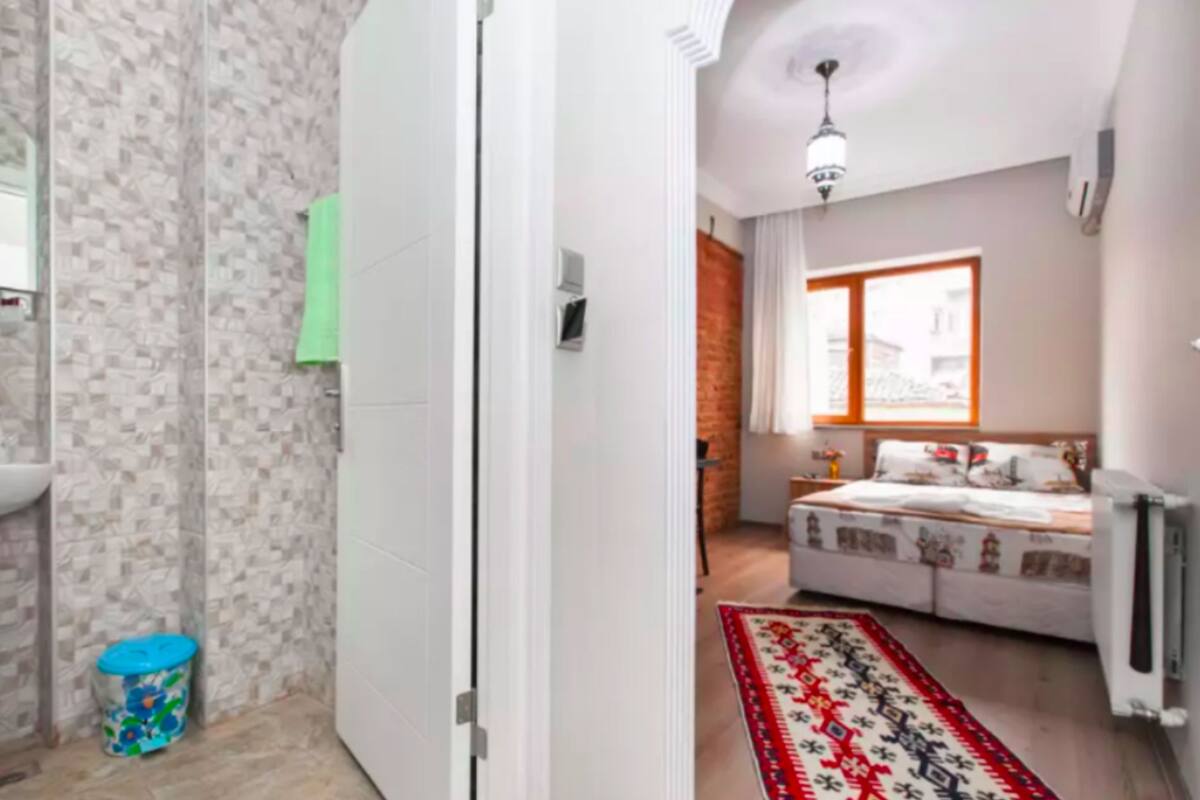 A bedroom with a bed, a window, and a patterned rug.