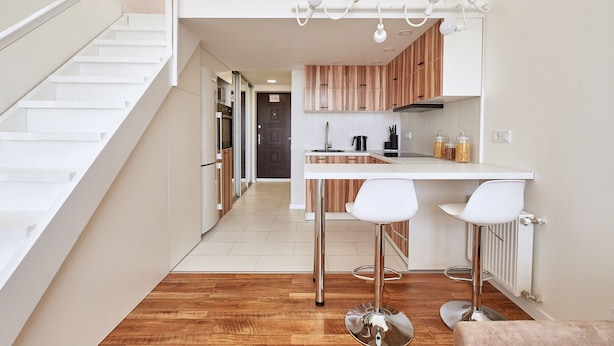 Eine moderne Küche mit weißen Schränken, einer Holz Arbeitsplatte und zwei weißen Barhocker.