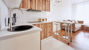 Eine moderne Küche mit Holzausstattung, einem Edelstahlspülbecken und einer Bar mit Hockern.