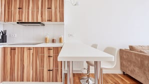 Eine moderne Küche mit Holzschränken, einer weißen Arbeitsplatte und einem Essbereich mit weißem Tisch und Stühlen.