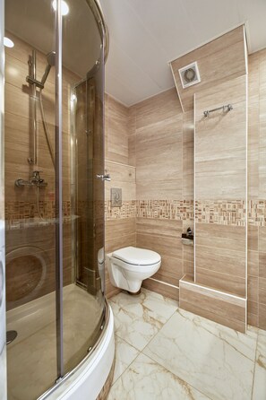 Un baño moderno con ducha acristalada, inodoro y lavamanos.