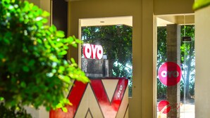 Un comptoir d’accueil avec une enseigne « OYO », une porte vitrée et un panneau circulaire rouge sur un pilier.
