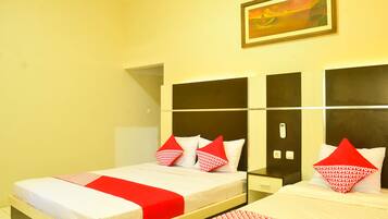 Habitación de hotel con dos camas, cada una con ropa de cama roja y blanca, un cuadro en la pared y una mesita entre las camas.
