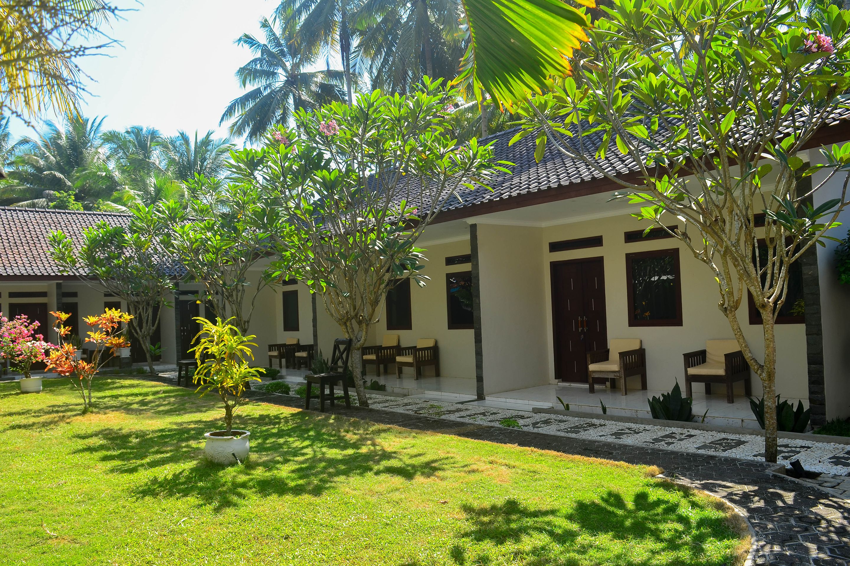 A building with a tiled roof, outdoor seating, and lush greenery.
