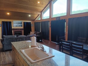 A spacious living area with a fireplace, a dining table, and a kitchen with a granite countertop and sink. - LOWEST SUMMER RATES ON THE WHITE RIVER! AMAZING FLY & SPIN FISHING IN BACKYARD! (Flippin)