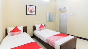 A hotel room with two beds, each with white bedding and red accents, a framed picture on the wall, and a door with a mirror. - Super OYO 890 Dewi Fortuna Guest House (Depok)