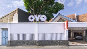 A building with a large sign reading "OYO" and a car parked in the driveway. - Super OYO 890 Dewi Fortuna Guest House (Depok)
