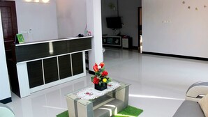 A reception area with a reception desk, a clock on the wall, and a flower arrangement on a table. - OYO 783 Grand Mentari Guest House (Bengkulu)