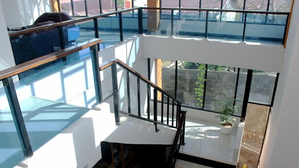 A multi-level interior with glass railings, a staircase, and a potted plant. - OYO 783 Grand Mentari Guest House (Bengkulu)