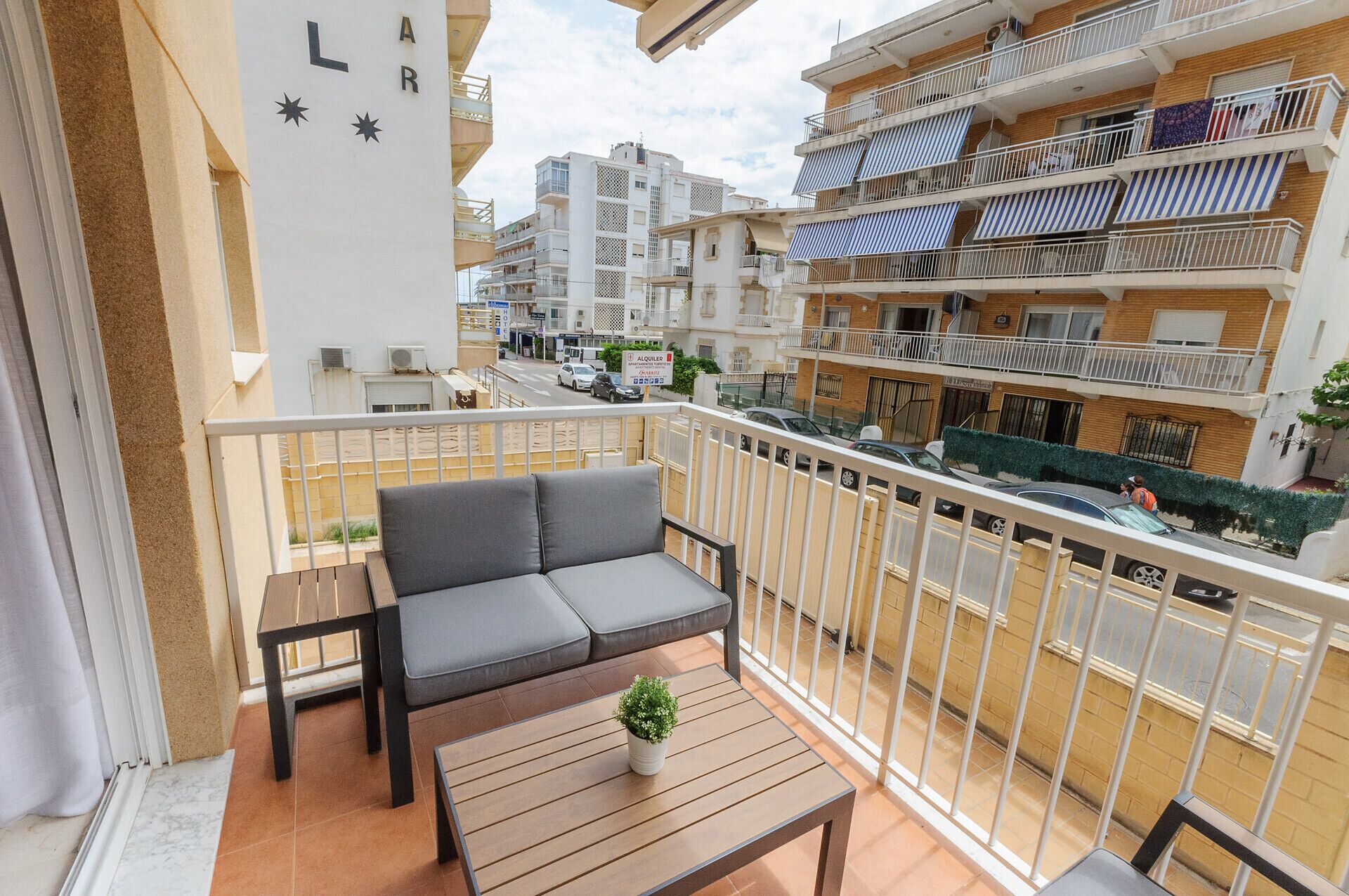 A balcony with a sofa, a small table, and a potted plant.