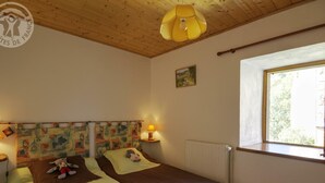 Une chambre avec deux lits, un plafond en bois, une fenêtre et un tableau au mur.