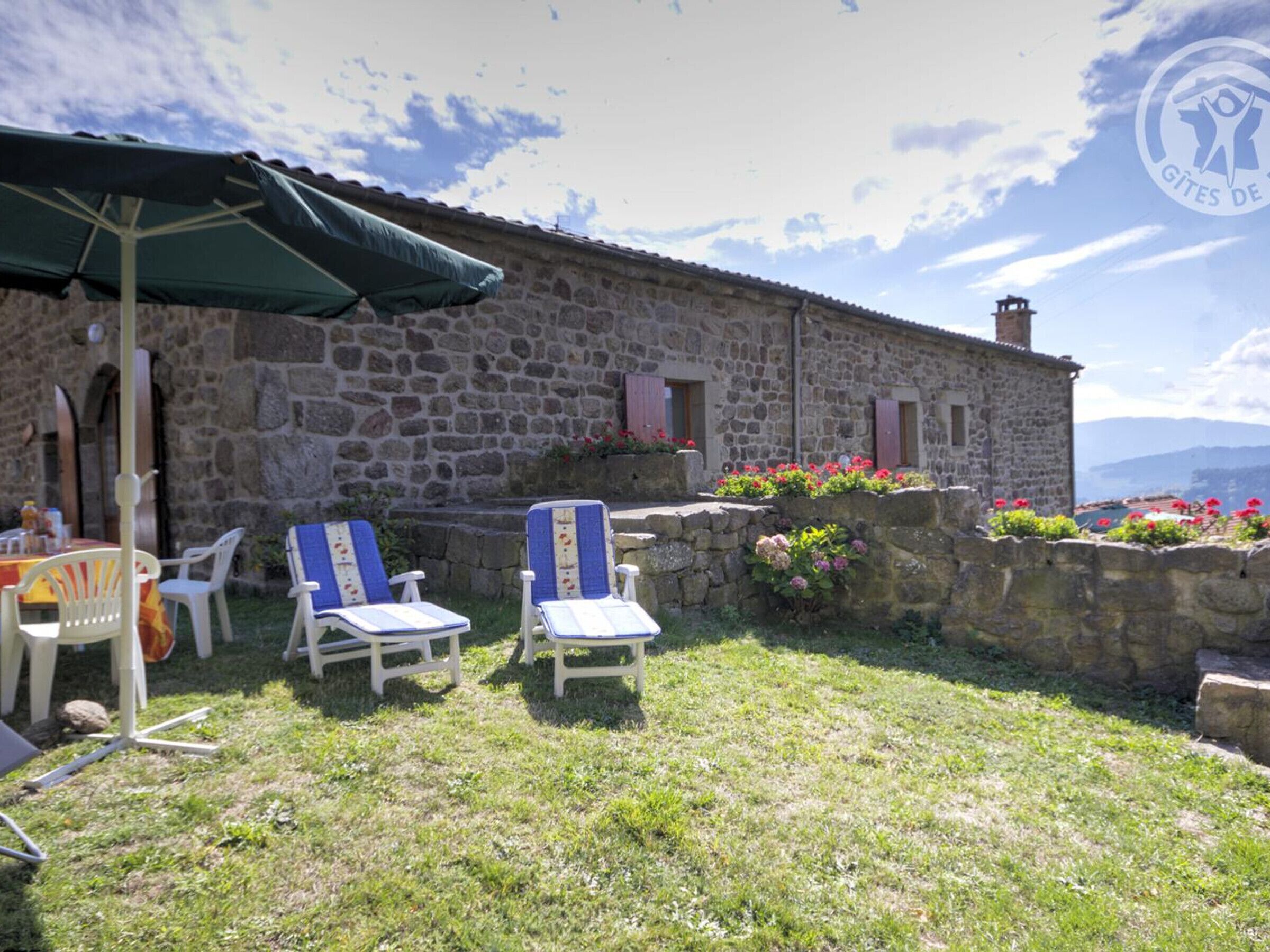 Un edificio de piedra con un patio que incluye asientos al aire libre y vistas del paisaje.