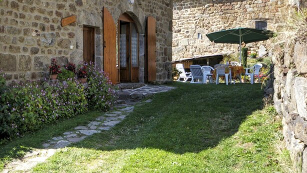 Un bâtiment en pierre doté d’un jardin, d’un espace extérieur aménagé pour s’asseoir et d’un mur en pierre.