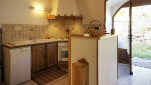 Une cuisine équipée d’un lave-vaisselle encastré, d’une cuisinière et d’un évier. On y trouve un meuble en bois et un petit tabouret en bois.